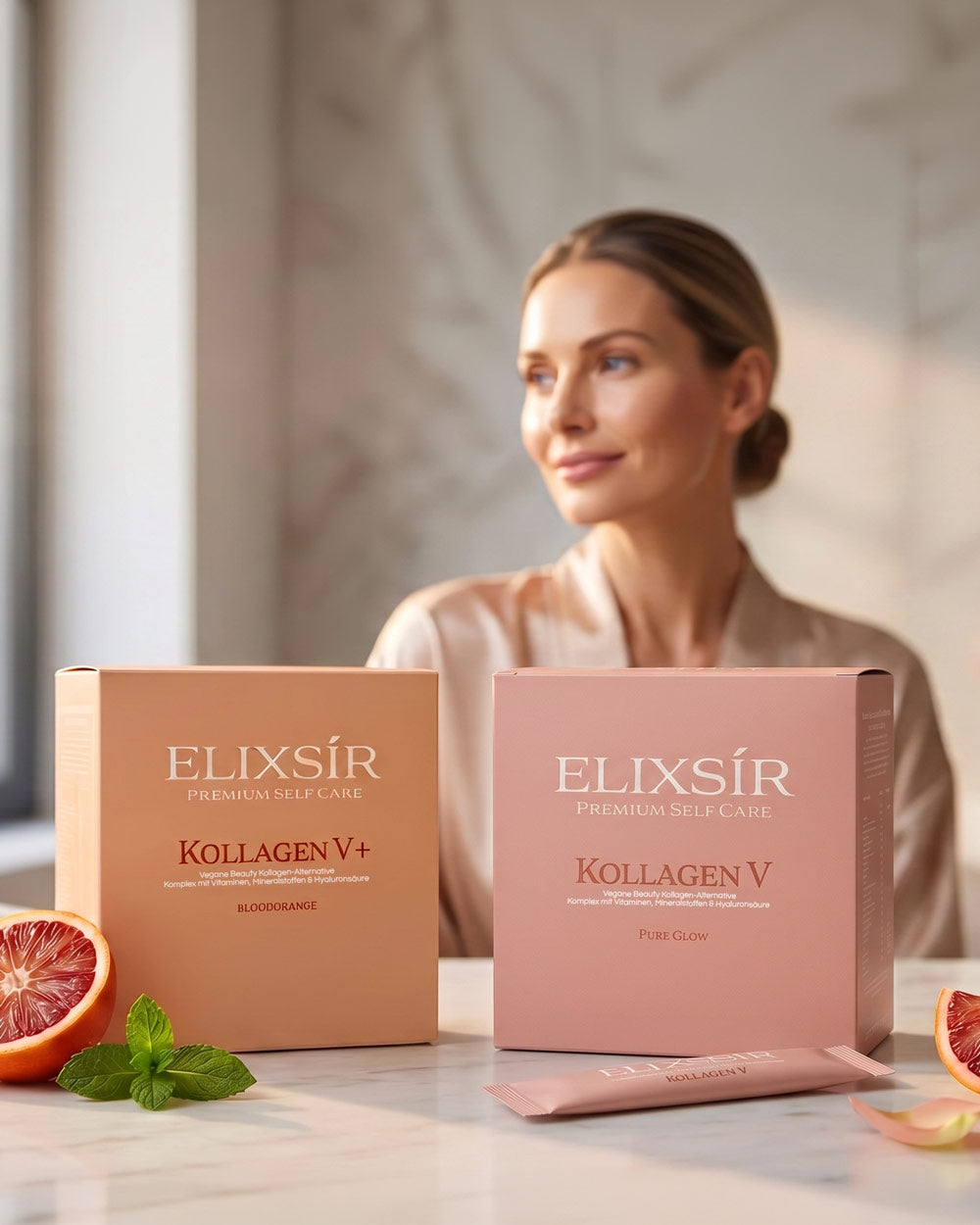 Frau im rosa Seidenhemd hinter den Elixsír Boxen Kollagen V+ und Kollagen V, davor Blutorangenscheibe, Minze und Marmor